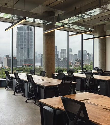 Office space with desks, chairs, large windows and a city view
