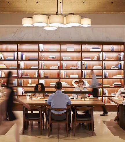 Warmly lit coworking space with bookshelves