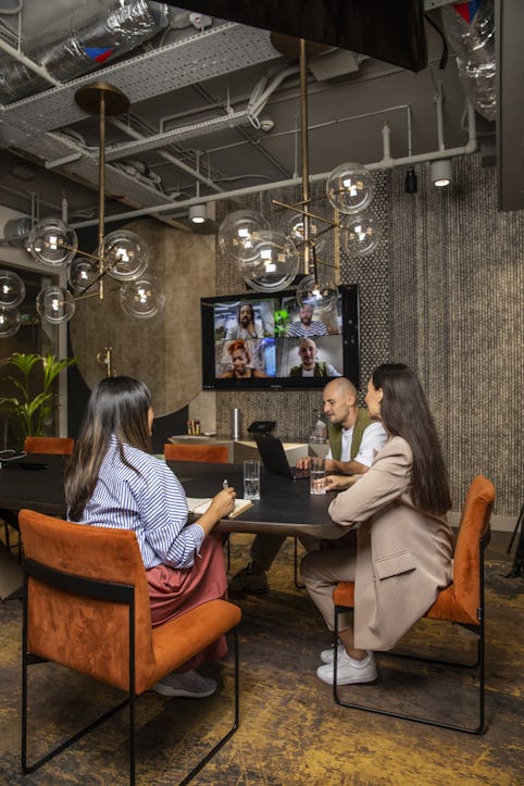 A team hybrid working in a meeting room with a large screen